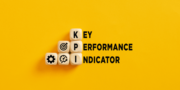 The words ‘Key Performance Indicator’ appear on a yellow background. The letters ‘KPI’ are abbreviated on wooden cubes, accompanied by matching icons.