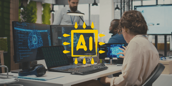 eine Frau sitzt am Schreibtisch. Vor ihr sind mehrere Bildschirme auf denen groß 