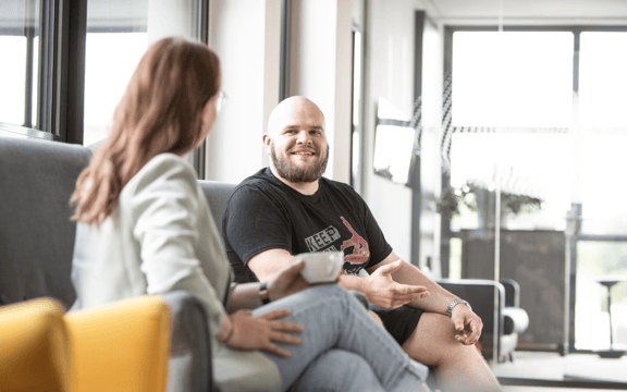 zwei Personen sitzen in Sesseln und unterhalten sich bei einem Kaffee