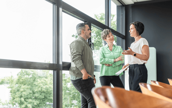 drei Personen stehen in einem Kreis und unterhalten sich