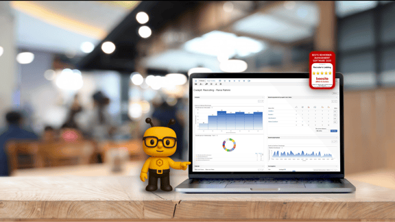 Ein Laptop steht auf einem Tisch, darauf sieht man das Cockpit der beesite. Die beeiste-biene zeigt auf den Bildschirm. Das Siegel 