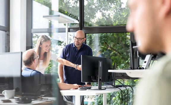 Teamwork im modernen Büro: Drei Personen arbeiten gemeinsam am Bildschirm – digitales Recruiting mit beesite HR-Software.