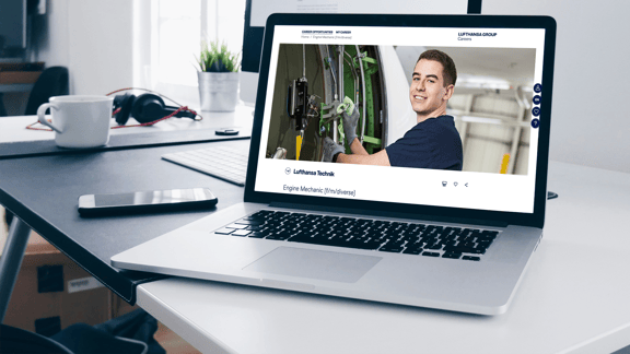 A laptop shows a Lufthansa careers page with a smiling employee in a warehouse and a job advertisement - a symbolic image for a reference to the successful use of the beesite.