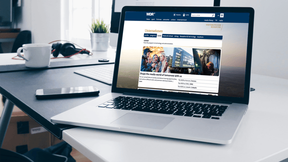 A laptop shows the career page of the WDR with pictures of people and a building - symbolic image for a reference of the successful use of the beesite.